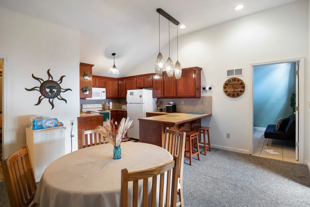 An open-concept dining area seamlessly connected to the kitchen, featuring a large dining table, kitchen island, and pendant lights. The inviting setup is ideal for shared meals, celebrations, and social gatherings, reinforcing the open, communal layout of the space.
