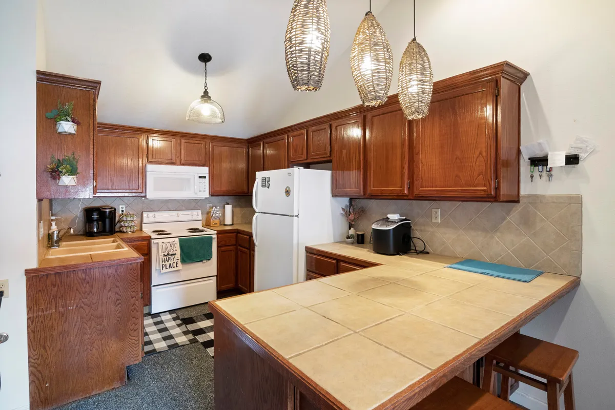 An inviting kitchen featuring a central island, hanging lights, stainless steel appliances, and distinctive checkerboard flooring. The setting suggests lively family gatherings and effortless group dining with plenty of room for everyone.