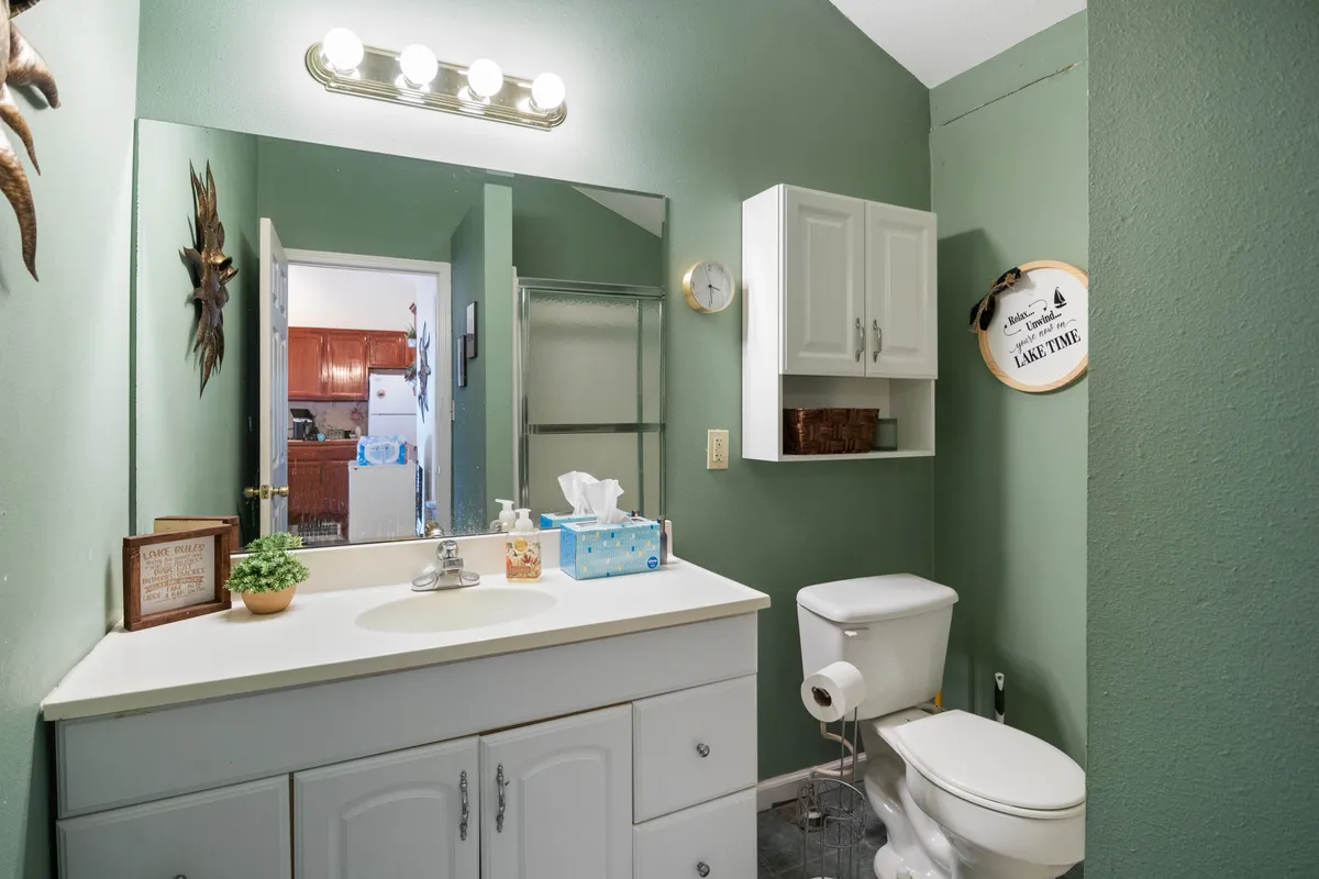 A modern bathroom with a vanity, large mirror, shower stall, and decorative wall art. The clean and bright space is ideal for personal grooming and pampering, echoing the boutique touches mentioned in the content.