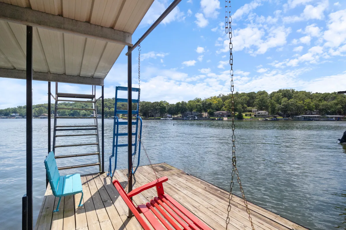 A close-up view of a dock area with a red swing and blue ladder, offering direct access to the water. The dock surface and swinging seat suggest a playful and relaxed environment, ideal for families or friends who want to fish, swim, or simply unwind right at the water's edge.